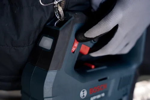 The Bosch GFP18V-10 18V Grease Gun being held by a professional in close-up visualization.