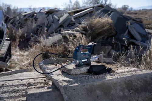 The Bosch GFP18V-10 18V Grease Gun on concrete surrounded by a construction area.