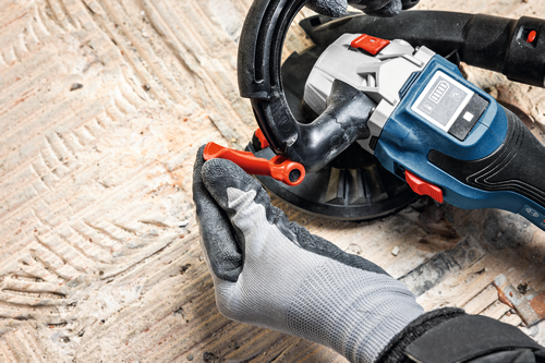 The close-up image of worker using the Bosch GBR18V-15S 5 In. 18V Concrete Surface Grinder to grind a hard concrete floor.