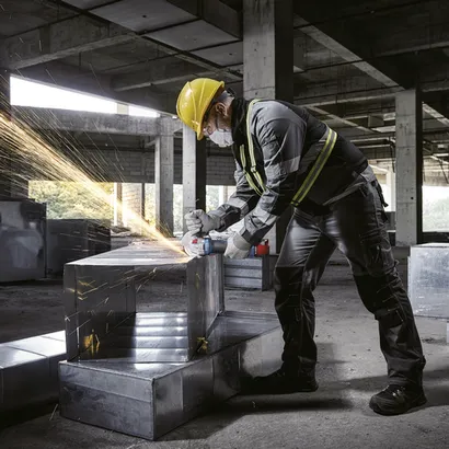 Worker using the Bosch GWX18V-8-2N 18V X-LOCK 4-1/2 In. Angle Grinder for cutting a steel plate.