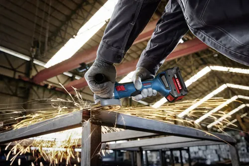 Worker using the Bosch GWX18V-8-2N 18V X-LOCK 4-1/2 In. Angle Grinder for cutting a steel plate.