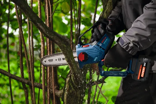The worker using the Bosch GKE18V-20 18V Pruning Saw with Expert Battery for cutting a branch from a small tree.