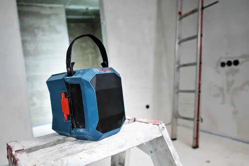 Image of Bosch GPB18V-1CN 18V Jobsite Bluetooth® Speaker on top of a ladder, in the middle of a room under renovation.