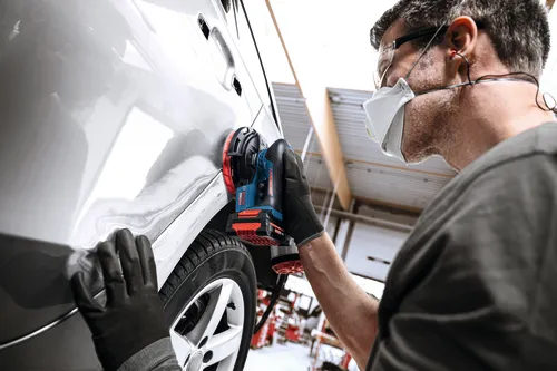 Image of worker using the Bosch EXEX18V-150-5N Random Orbit 18V 6” Random Orbit Sander (3/16”) for finishing a car.