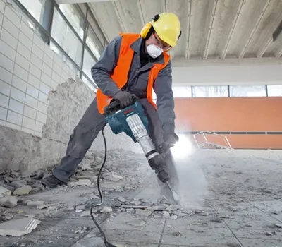 Person wearing safety equipment operating a demolition hammer.