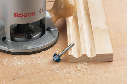 Bosch router next to a piece of wood with routed grooves and a wood-carving bit.