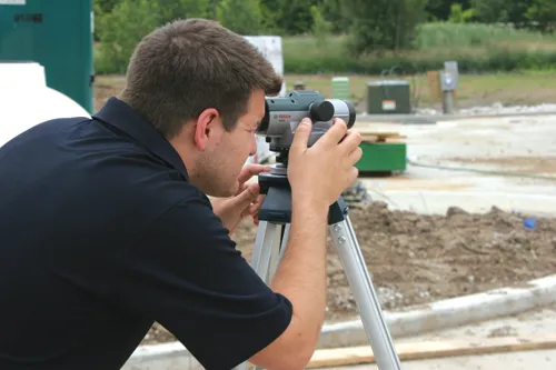 A person looks through a BOSCH GOL32D surveying level mounted on a tripod.