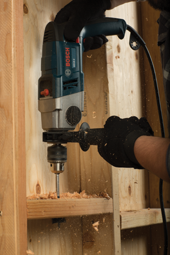 Bosch HD18-2 taladrando una estructura de madera; persona con guantes negros sujeta el taladro.