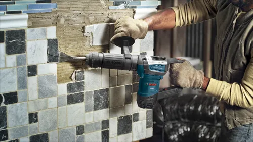 Una persona con piel oscura quitando azulejos con un Boschhammer DH507 de Bosch.