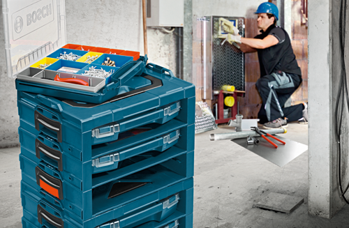 Organizador de herramientas Bosch con tornillos y un trabajador en el fondo.