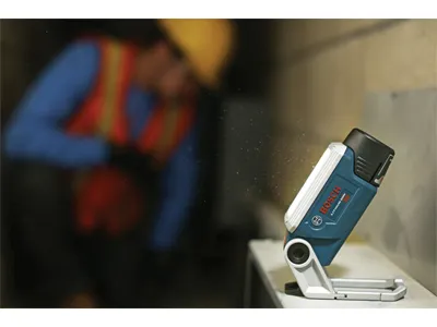 Luz LED de iones de litio Bosch iluminando un área de trabajo, con trabajador en el fondo.