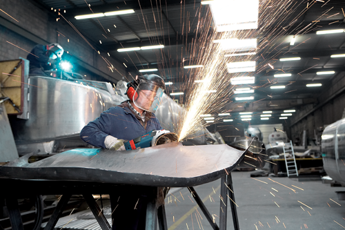 Bosch LBM 18-125 S amoladora en uso por una persona que lleva equipo de protección, con chispas volando.