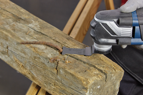 Hoja de corte de metal Bosch AIZ 32 AB cortando un clavo en una pieza de madera, sujeta por una multiherramienta StarLock Plus.