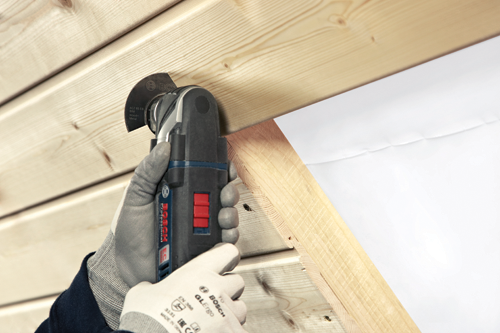 Hoja Bosch ACZ 85 EB cortando madera, una mano enguantada sujeta una multiherramienta Bosch Professional EC.