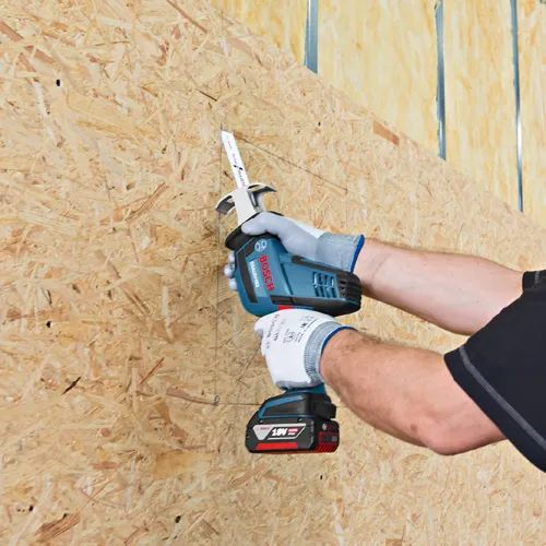 Sierra sable Bosch GSA18V-083 utilizada para cortar una línea en un panel de madera por una persona que lleva guantes.