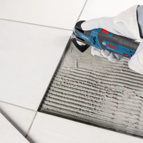 Bosch GOP12V-28 Starlock herramienta multifunción cortando entre baldosas.