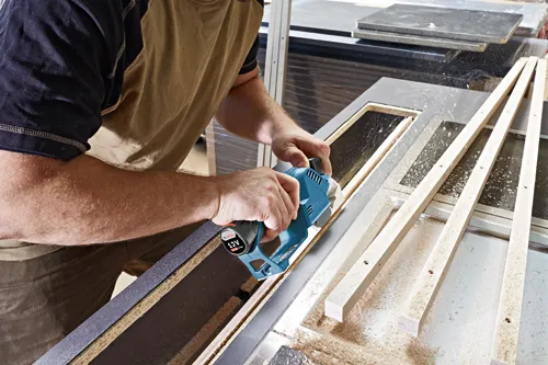 Una persona utilizando una herramienta eléctrica Bosch sobre madera; la herramienta tiene "12V 2.0 Ah Li-Ion" en ella.