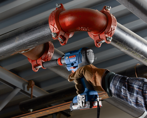 Llave de impacto Bosch GDX18V-1600 en uso, junto a una tubería con el texto 'ALLIED DYNA FLOW ABF 3 500 PSIUSA', con batería Core18V 4.0 Ah.