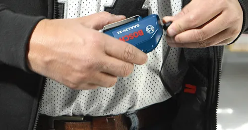 Hombre sosteniendo un Bosch GAA12V-21 azul.