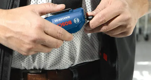 Persona conectando un cable negro a una herramienta azul Bosch GAA12V-21.