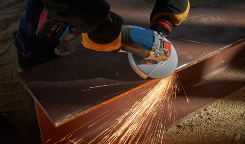 Persona utilizando una amoladora angular Bosch para cortar una viga metálica; chispas saltan de la acción de corte.