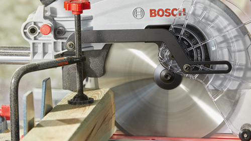 Bosch sierra con marca denominativa "BOSCH" y código "225699-100A", cortando tabla de madera.