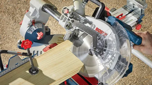 Sierra ingletadora Bosch cortando una pieza de madera, con el nombre de la marca BOSCH visible.