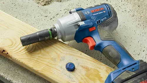 Bosch GDS18V-330PC HD llave de impacto a batería con motor sin escobillas y vaso Cr-Mo de 9/16, junto a madera y un perno.