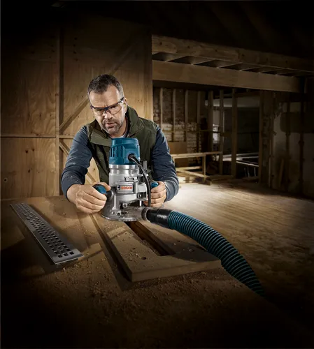 Hombre en un taller utilizando una fresadora con cable Bosch sobre madera.