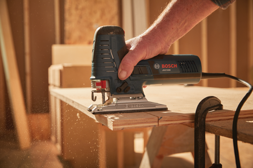 Bosch JS572EB sierra caladora cortando madera; mano de una persona sujetando la herramienta.