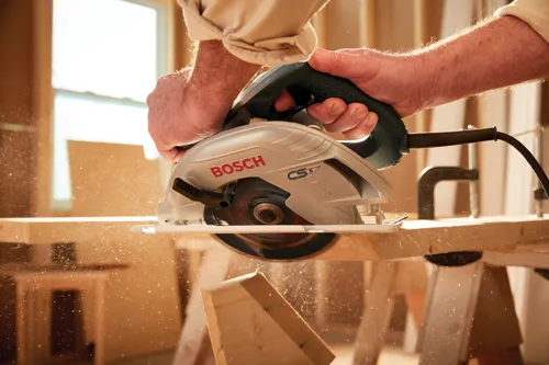 Hombre utilizando la sierra circular con cable CS5 de Bosch para realizar un corte en ángulo en madera.