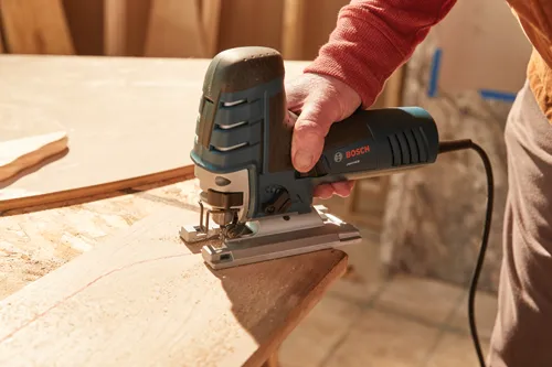 Sierra caladora Bosch JS470EB siendo utilizada para cortar una pieza de madera.