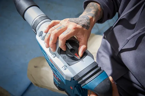 Hombre con tatuajes en la mano activando el interruptor de potencia turbo en el martillo combinado Bosch.