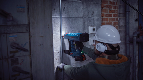 Bosch GNB18V-12 clavadora, con persona que lleva gafas de seguridad y casco, operando la herramienta en pared de hormigón.