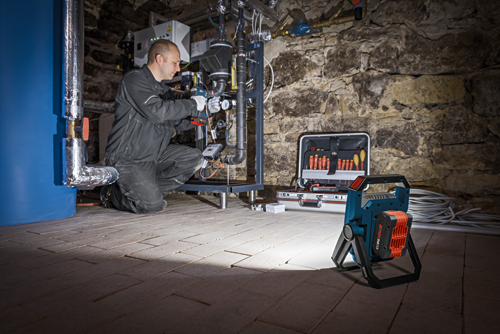 Hombre utilizando la lámpara de trabajo inalámbrica Bosch para iluminar el área de trabajo.