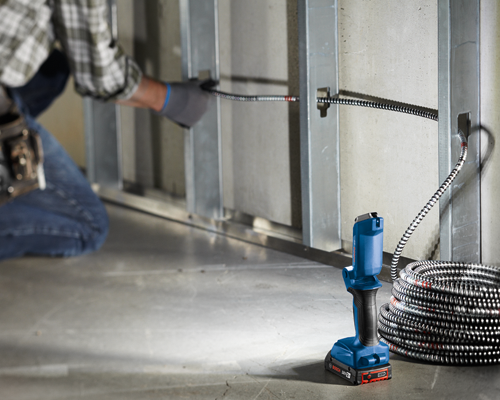 Bosch Taladro Inalámbrico 18V 2Ah, con cable metálico en espiral junto a una pared con estructura metálica.