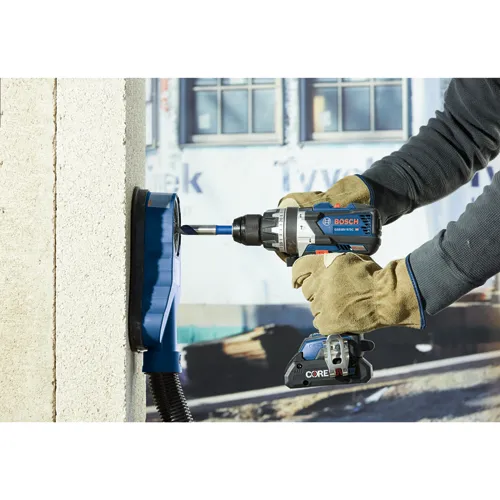 Persona con guantes utilizando un taladro BOSCH GSB18V-975C HD para perforar una pared de hormigón.