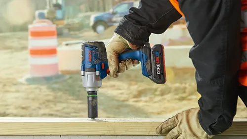 Llave de impacto a batería Bosch GDS18V-330PCHO, con batería CORE18V 4Ah, sostenida por una persona que lleva guantes.