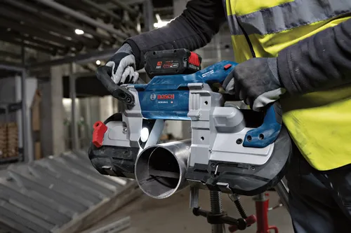 Bosch GCB18V-5 HD sierra de cinta cortando un tubo; la herramienta funciona con una batería de 18 V.
