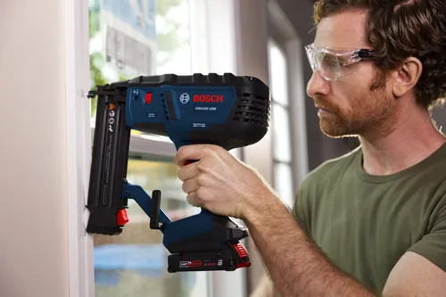 Bosch GNH18V-18M Clavadora de Acabado de 18 GA siendo utilizada por una persona que lleva gafas de seguridad.