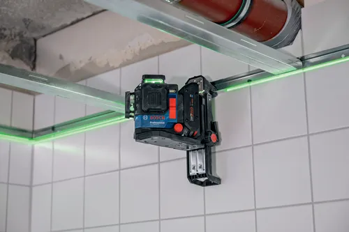 Nivel Bosch Professional GLL3-80CG, con líneas láser verdes, montado en una pared de azulejos blancos.