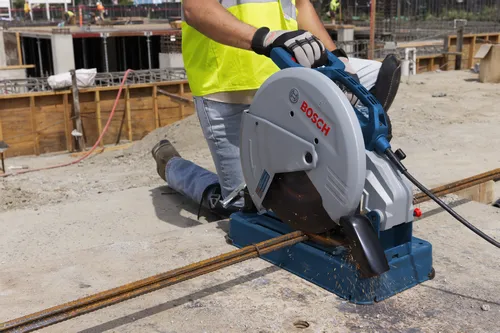 Persona utilizando una sierra de corte de metal Bosch, cortando varillas de refuerzo en una obra.