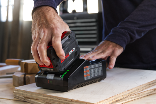 Una persona inserta una batería CORE18V en un cargador. La batería y el cargador son negros y rojos.