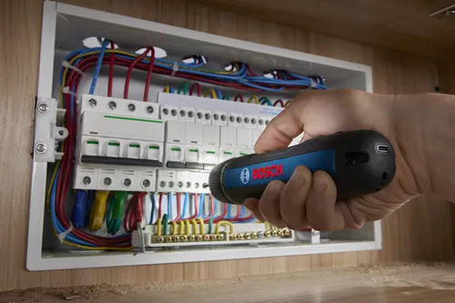 Someone using a Bosch GSD4V-35 rechargeable screwdriver to work on an electrical box.