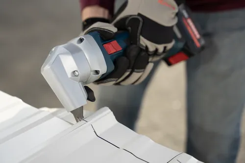 The worker using the GNA18V-16E 18V 16-Gauge Nibbler With Lock-On Slide Switch to cutting a polycarbonate tile.