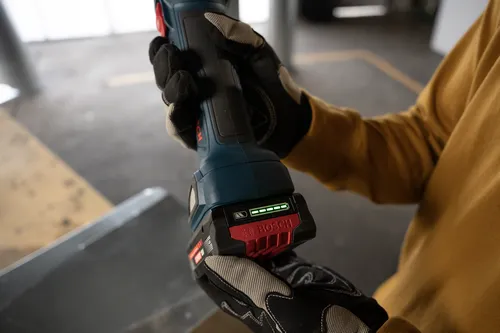 A worker attaching a Bosch EXBA18V-40 EXPERT 18V Lithium-Ion 4 Ah High Power Battery to a power tool.