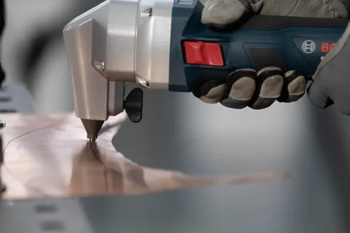 The worker using the GNA18V-16E 18V 16-Gauge Nibbler With Lock-On Slide Switch to cutting a copper plate.