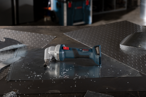 The Bosch GNA18V-16EN 18V 16-Gauge Nibbler With Lock-On Slide Switch without a battery on a workshop table.