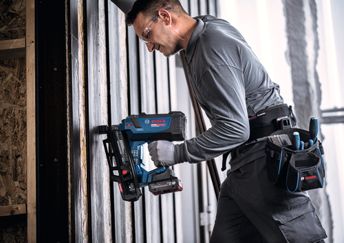 Imagen de un trabajador usando la pistola de clavos para estructuras Bosch EXNH18V-90MRN EXPERT de 18 V en paredes de madera.