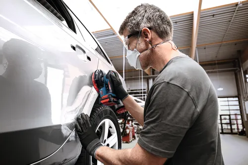Imagen de un trabajador usando la lijadora roto orbital Bosch EXEX18V-150-5N de 18 V y 6" (3/16”) para un acabado automotriz.